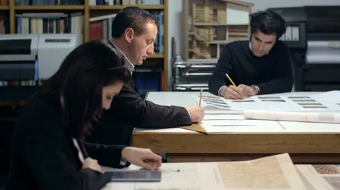 Three architects at work with calculators and printed projects: teamwork Stock Footage 49775674