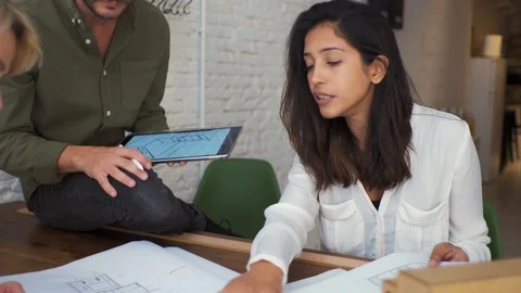 Three architects working together at desk in an office Stock Footage 125631589