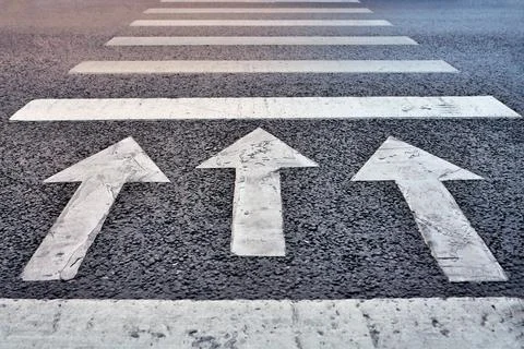 Three arrows on asphalt point forward a powerful symbol of purpose, progress Stock Photos