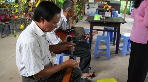Three asian men are playing musical instruments for tourists in vietnamese Vídeos de archivo 67426008