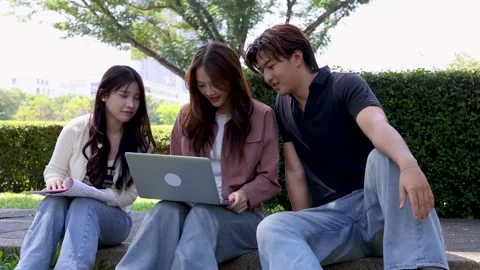 Three Asian University Students Study Together Outdoors on Campus with Laptop Stock Footage 329461674