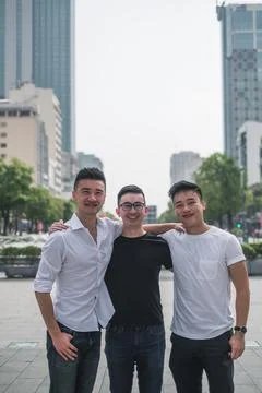 Three asian young men standing on the street and smiling. Stock Photos