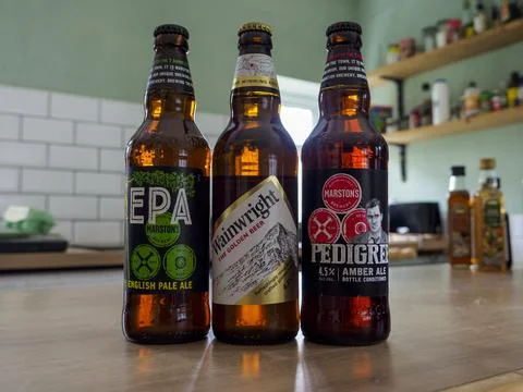 Three assorted beer bottles placed on a kitchen counter. Stock Photos