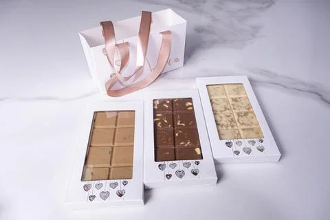 Three assorted chocolate bars next to a bag. Stock Photos