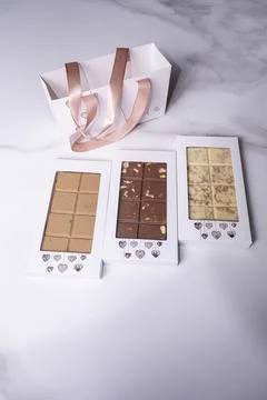 Three assorted chocolate bars next to a bag vertical. Stock Photos