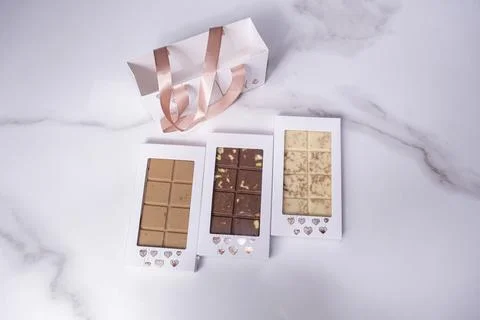 Three assorted chocolate bars next to a bag top view. Stock Photos