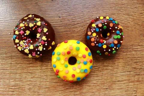Three assorted donuts on a wood background Stock Photos