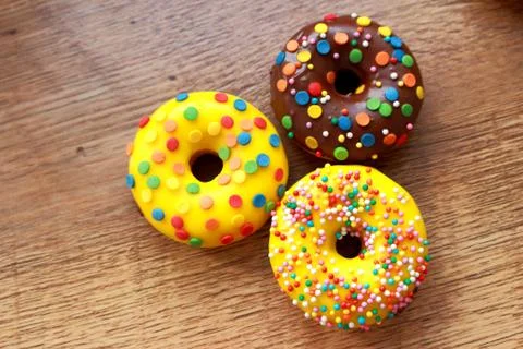 Three assorted donuts on a wood background Stock Photos