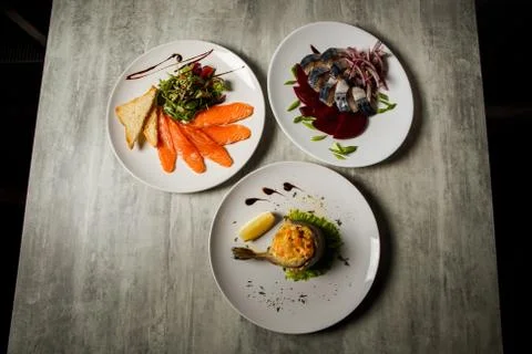 Three assorted restaurant dishes of mackerel, salmon, and trout and vegetable Foto stock