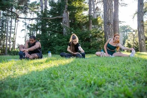 Three athletes during a workout perform a stretching exercise, multi-ethnic.. Stock Photos