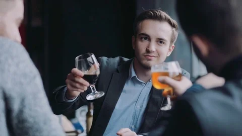 Three attractive friends raise their beer mugs in a toast, then have a sip Video stock 74801676