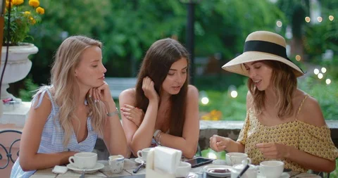 Three attractive girlfriends guessing at the coffee grounds sitting in a cafe Stock Footage 91724480