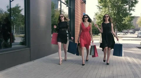 Three attractive young ladies are walking with their purchases Stock-Footage 67864591