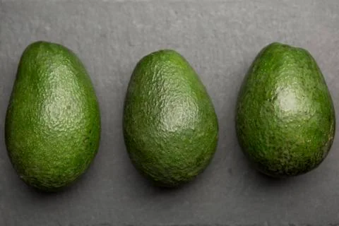 Three avocado top view on a dark background . Stock Photos