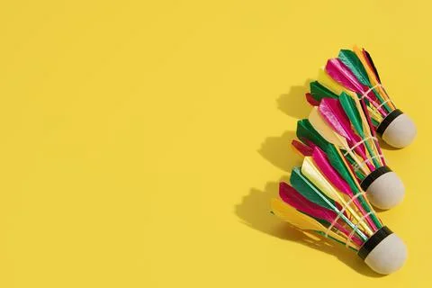 Three badminton shuttlecocks with multi-colored feathers on a yellow background Stockfoto's