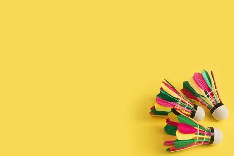 Three badminton shuttlecocks with multi-colored feathers on a yellow background Stock Photos