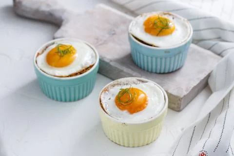 Three baked egg in ramekins on white background Stock Photos