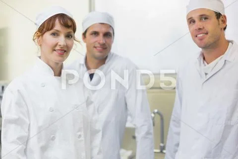 Three bakers posing in a kitchen Stock Photos