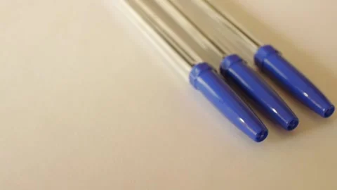 Three ballpoint pens with blue caps rotate in a circle on the table. Stock Footage 167178564