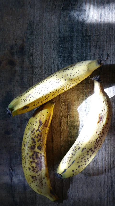 Three bananas on the table, under random sun rays. Stock Footage 308485282