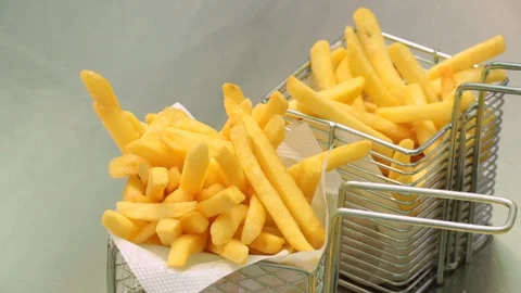 Three baskets and two plates of golden crispy french fries being displayed on Stock Footage 127715820