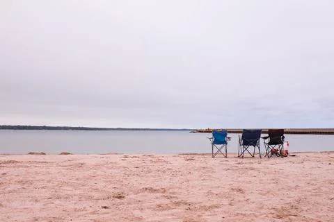 Three beach chairs standing on the sandy shore 스톡 사진