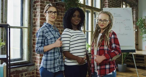 Three beautiful and young multiethnical women standing in the urban co-working Stock Footage 100992404