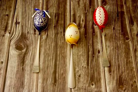 Three beautiful coloured Easter eggs laid on a table, each on one spoon Foto stock