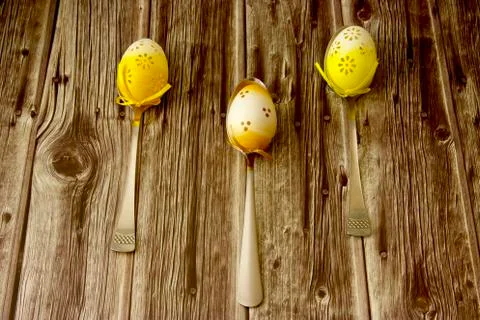 Three beautiful coloured Easter eggs laid on a table, each on one spoon Stock Photos