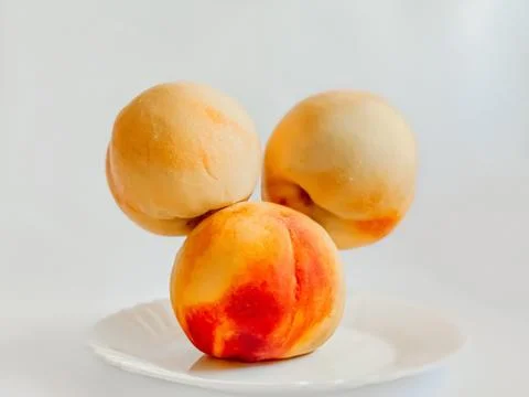 Three beautiful peaches levitating amusingly over a white plate. Healthy food Stock Photos