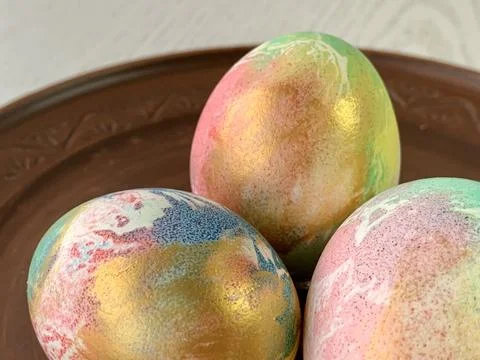 Three beautifully decorated eggs feature vibrant colors and patterns, placed on Foto stock