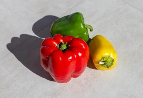 Three bell peppers on a light background. Red, green, and yellow produce with Stock Photos