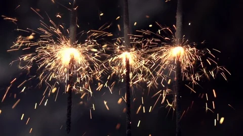 Three Bengal or Indian lights, or sparklers, hanging on dark background Stock Footage 86429628