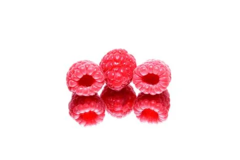 	Three berries of a raspberry are reflected in a mirror Stock Photos