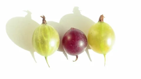 Three berries, red and green gooseberries on a white background roll aside as Stock Footage 159657496