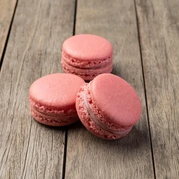 Three berry macarons stacked over wooden table Fotos Stock