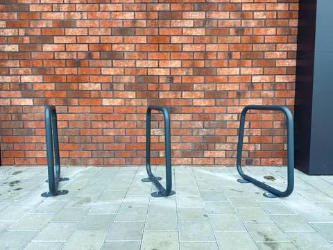 Three bicycle racks against a brick wall in sunlight Stock Photos