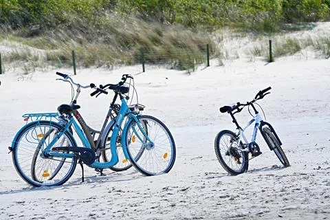 Three bicycles on a sandy beach. Two ofthem are city or trekking bikes.. Stock Photos