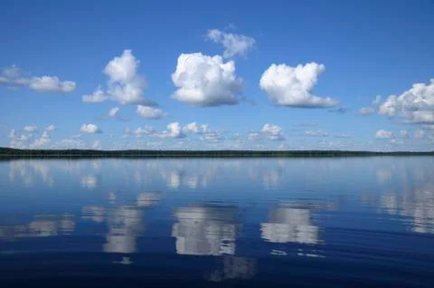 Three big clouds above the mirrored lake Stock Photos