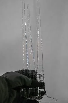 Three big icicles in a gloved hand Stock Photos