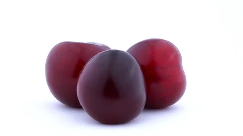 Three big purple maynard plums rotating on the turntable. Water drops appears Stock Footage 93632964