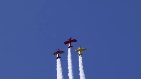 Three biplanes with smoke trails performing aerobatic maneuvers in clear bl.. Vídeos de archivo 333490025