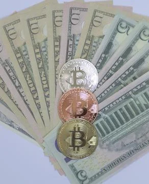 Three bitcoin coins in the shape of a triangle on a background of dollars Stock Photos