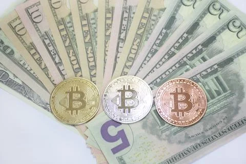 Three bitcoin coins in the shape of a triangle on a background of dollars Stock Photos