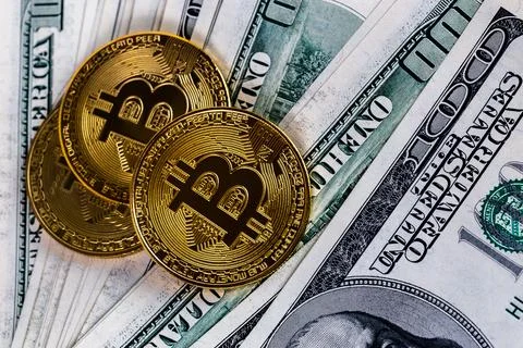 Three bitcoin shiners over us dollar banknotes close-up background Stock Photos