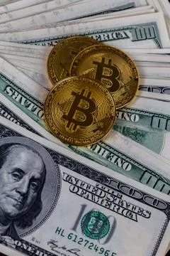 Three bitcoin shiners on paper us dollar banknotes background Stock Photos