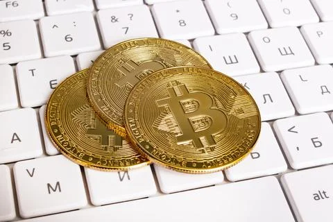 Three bitcoins on a computer keyboard closeup Foto stock