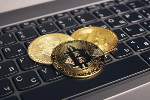 Three bitcoins on a computer keyboard closeup Stock Photos