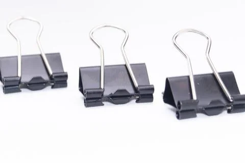 Three Black Binder Clips on White Background, Office Supplies, Close-up. Stock Photos