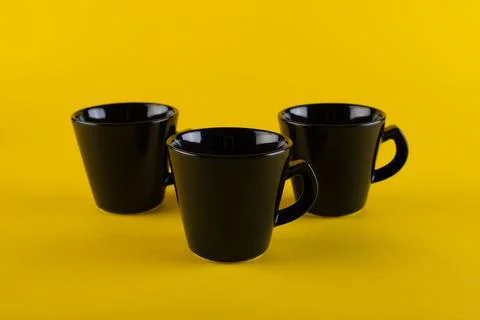 Three black cups on a yellow background. Coffee cups Stock Photos